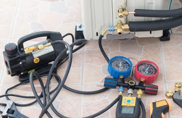 California HVAC Maintenance setup with manifold gauges and vacuum pump servicing outdoor AC unit